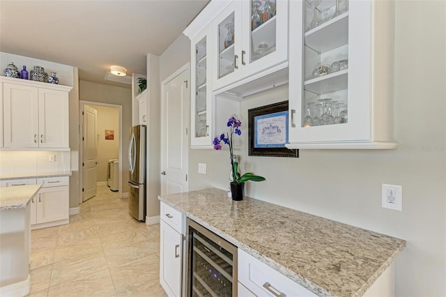 kitchen featuring light stone countertops, stainless steel fridge, white cabinetry, and beverage cooler