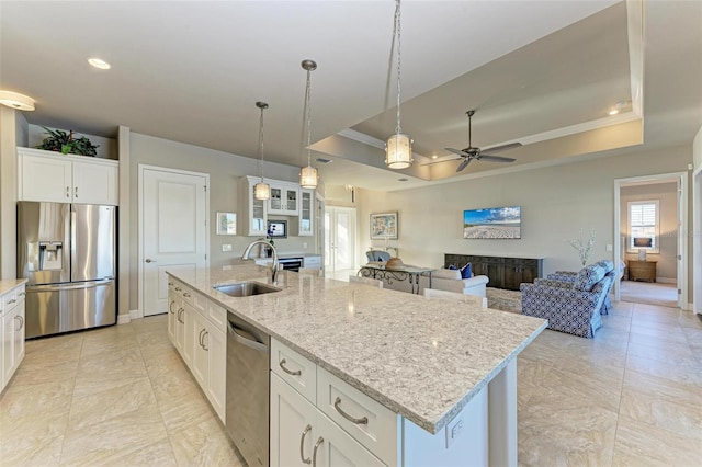 kitchen with a kitchen island with sink, white cabinets, a raised ceiling, sink, and stainless steel appliances