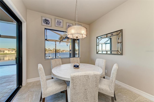 dining space featuring a water view and an inviting chandelier