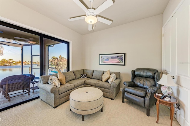 living room featuring light carpet, a water view, and ceiling fan