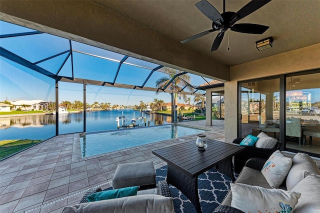 view of patio featuring glass enclosure, ceiling fan, a water view, and an outdoor living space