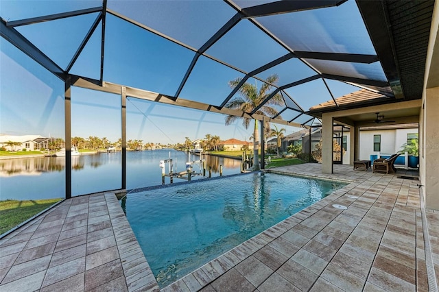 view of swimming pool featuring a dock, a lanai, ceiling fan, a water view, and a patio area