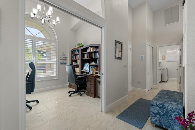 office with a chandelier, light tile patterned floors, a towering ceiling, and washer and dryer