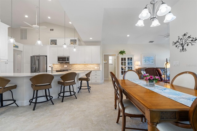 tiled dining space with ceiling fan with notable chandelier and high vaulted ceiling