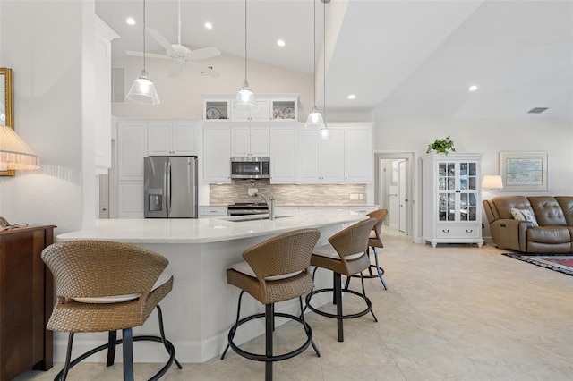 kitchen with sink, a breakfast bar area, decorative light fixtures, white cabinetry, and stainless steel appliances