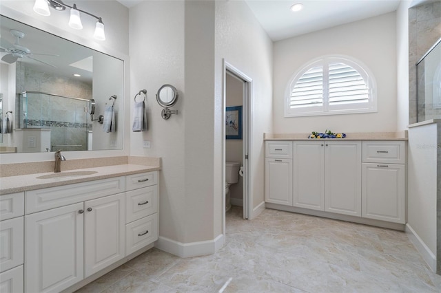 bathroom featuring an enclosed shower, ceiling fan, toilet, and vanity