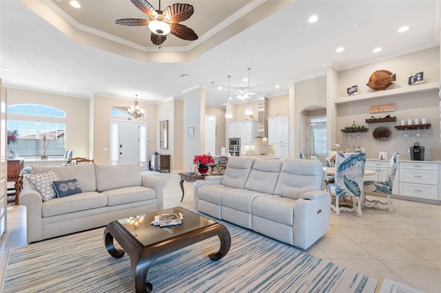 living room featuring ceiling fan with notable chandelier, light tile patterned flooring, and crown molding