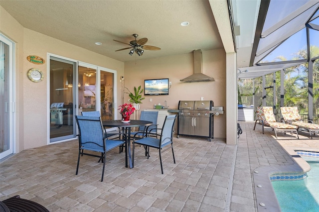 view of patio featuring glass enclosure, ceiling fan, sink, and area for grilling