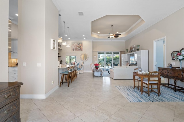 tiled living room featuring a raised ceiling, ceiling fan, and crown molding