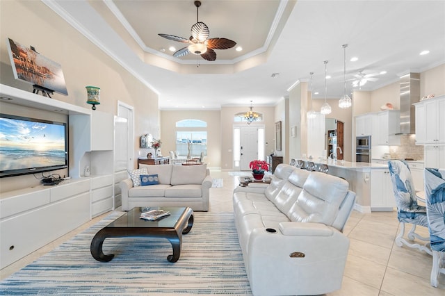 living room with light tile patterned floors, ceiling fan with notable chandelier, a raised ceiling, and crown molding