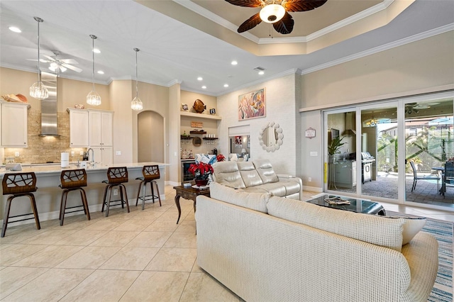 living room featuring ceiling fan, light tile patterned flooring, ornamental molding, and sink