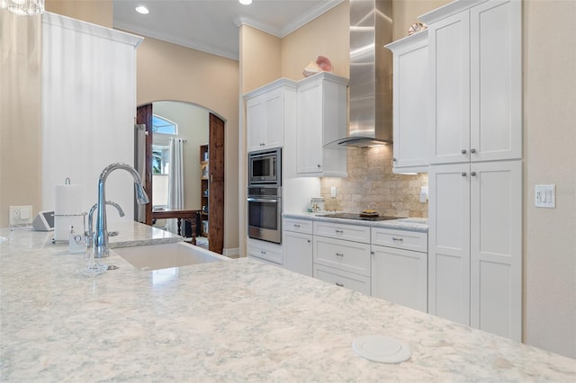 kitchen with white cabinetry, crown molding, wall chimney range hood, and appliances with stainless steel finishes