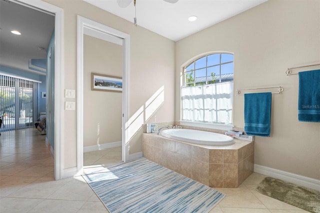 bathroom with tile patterned flooring, a relaxing tiled tub, and ceiling fan