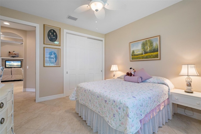 tiled bedroom with ceiling fan and a closet