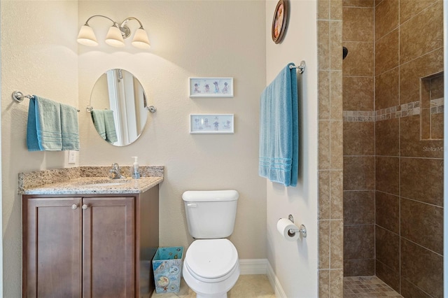 bathroom featuring a tile shower, vanity, and toilet