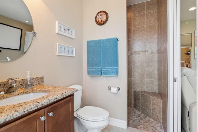 bathroom with a tile shower, vanity, and toilet