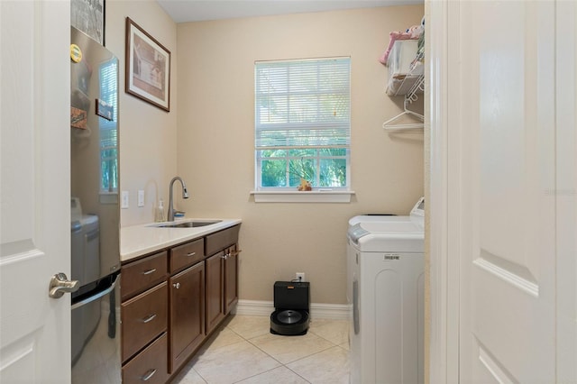 washroom with cabinets, washing machine and dryer, light tile patterned floors, and sink