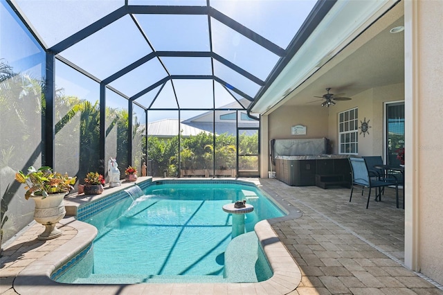 view of swimming pool with glass enclosure, pool water feature, ceiling fan, a patio, and a hot tub