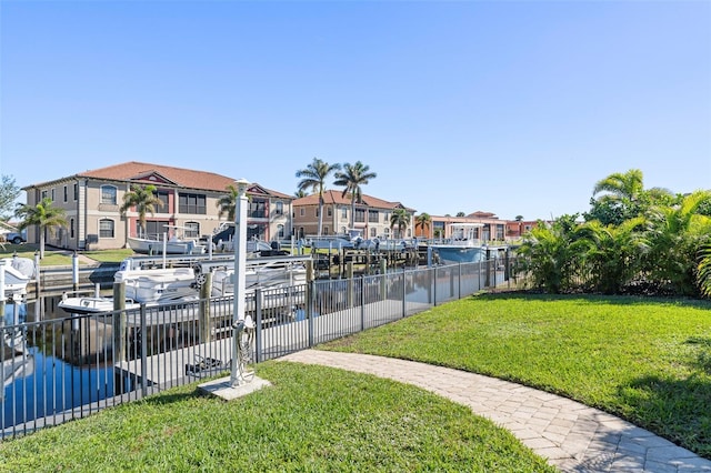 surrounding community with a boat dock, a water view, and a yard