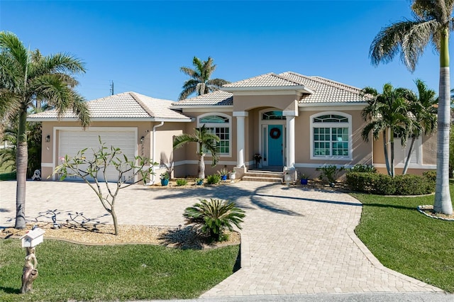 mediterranean / spanish house with a garage and a front lawn