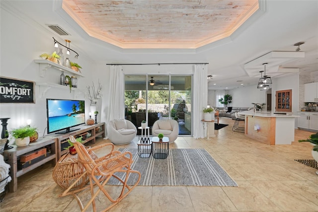 living room with ceiling fan, a raised ceiling, ornamental molding, and light tile patterned floors