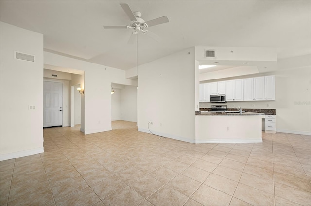 unfurnished living room featuring light tile patterned floors, ceiling fan, and sink