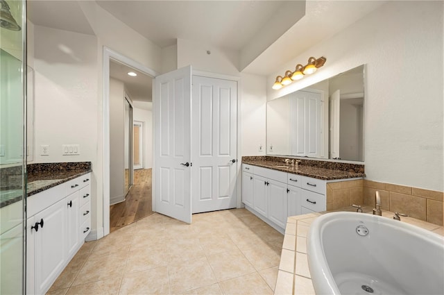 bathroom featuring tile patterned flooring, vanity, and a bath