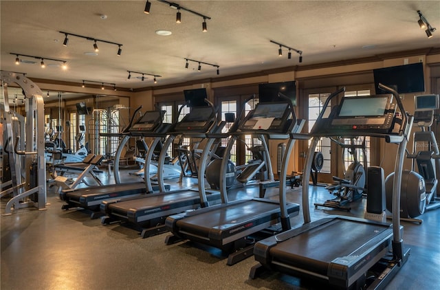 workout area with rail lighting and a textured ceiling