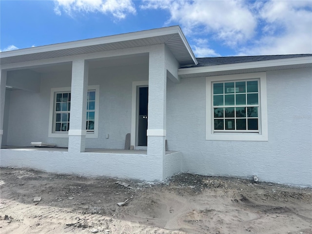 doorway to property with roof with shingles and stucco siding