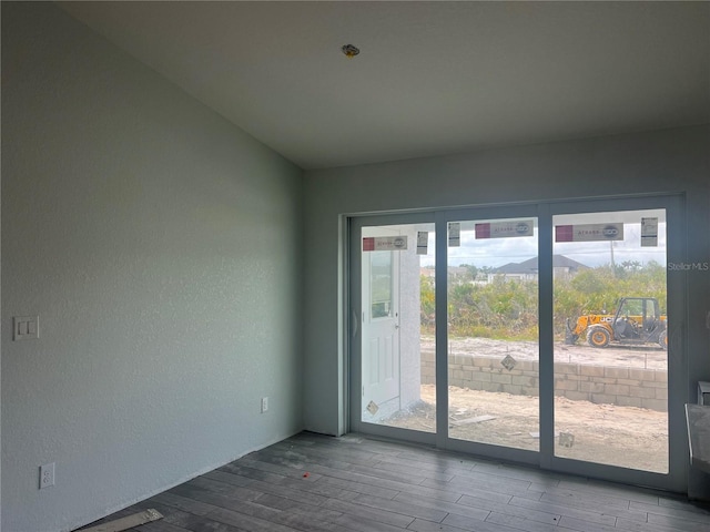 unfurnished room featuring a textured wall and wood finished floors