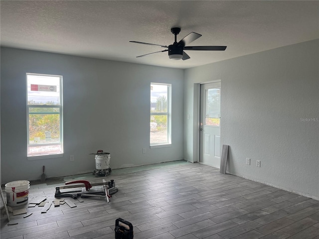 unfurnished room with light wood-type flooring, ceiling fan, and a textured ceiling