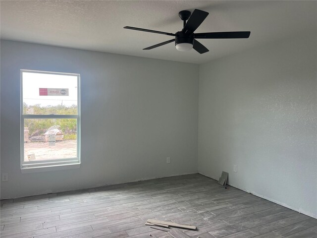 empty room featuring a textured ceiling, light wood finished floors, and a ceiling fan