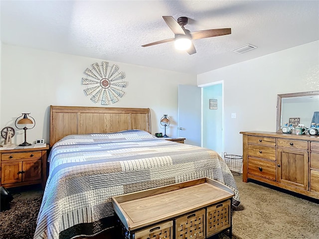 bedroom with ceiling fan, carpet flooring, and a textured ceiling