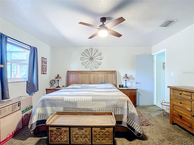 carpeted bedroom featuring ceiling fan and a textured ceiling