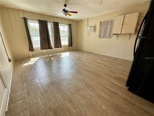 unfurnished room with ceiling fan, a wall mounted air conditioner, and a textured ceiling