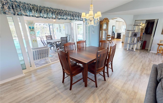 dining room featuring a chandelier, light wood-type flooring, and lofted ceiling