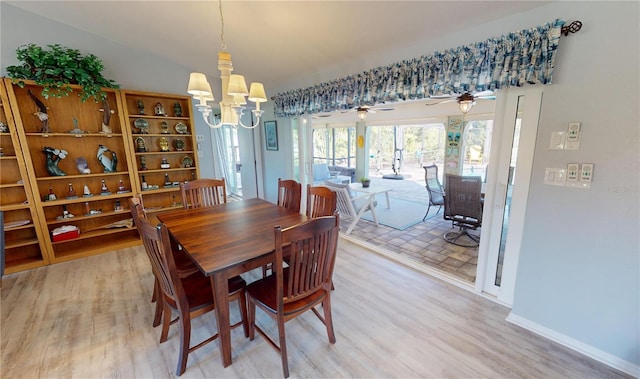 dining space featuring lofted ceiling, wood-type flooring, and ceiling fan with notable chandelier