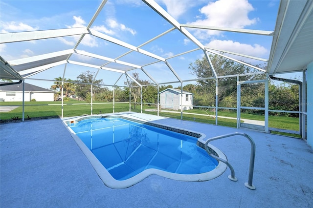 view of pool featuring glass enclosure, a storage unit, a patio area, and a lawn