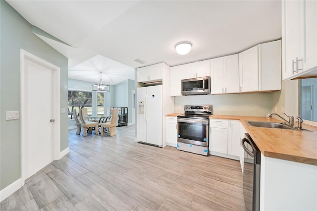 kitchen with white cabinetry, sink, stainless steel appliances, and wooden counters