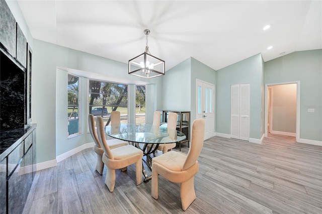 dining room featuring light hardwood / wood-style flooring, lofted ceiling, and an inviting chandelier