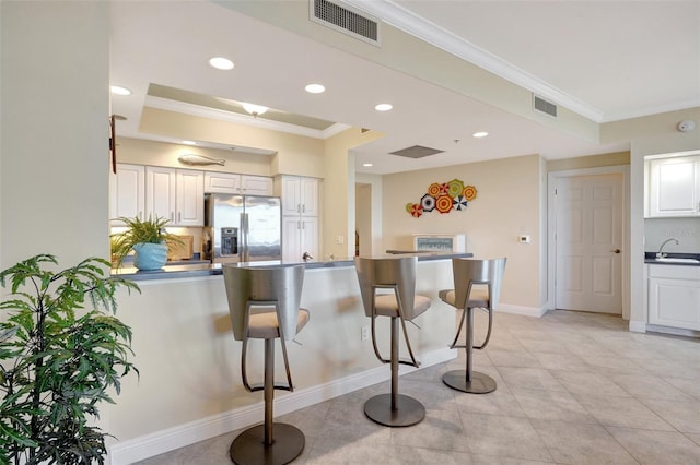 kitchen with kitchen peninsula, stainless steel fridge with ice dispenser, white cabinetry, and sink