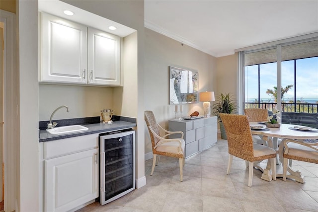 tiled dining space featuring wine cooler, ornamental molding, and sink