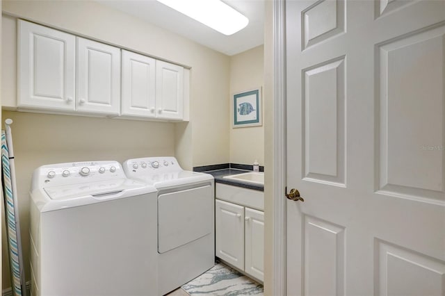 clothes washing area featuring washing machine and clothes dryer, sink, and cabinets