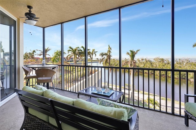 sunroom featuring ceiling fan and a water view