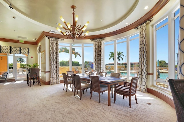 dining space with a water view, ornamental molding, light carpet, and an inviting chandelier