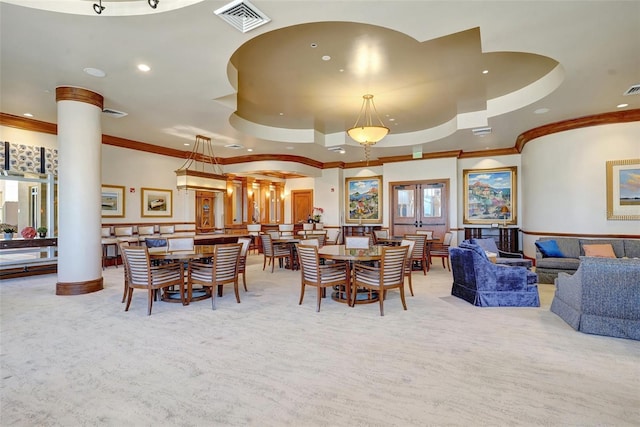 dining area featuring a raised ceiling, ornate columns, light colored carpet, and ornamental molding