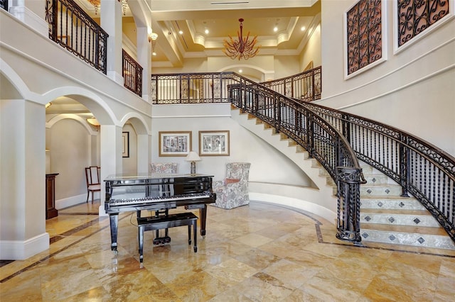 entrance foyer with a chandelier, beam ceiling, a towering ceiling, and crown molding