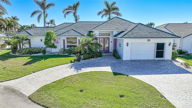 ranch-style home with french doors, a front yard, and a garage