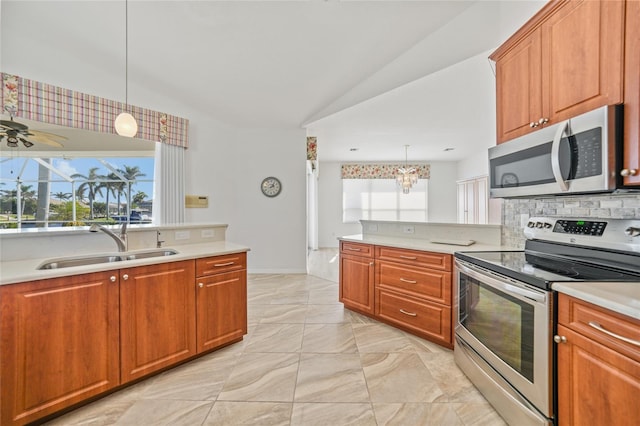 kitchen featuring sink, lofted ceiling, decorative light fixtures, ceiling fan with notable chandelier, and appliances with stainless steel finishes