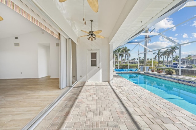 view of pool featuring a patio, glass enclosure, and ceiling fan